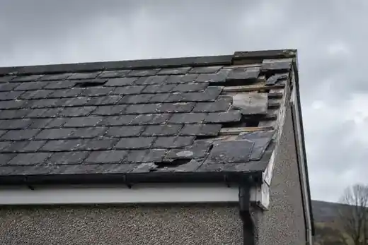 Storm-damaged slate roof with displaced and missing slates